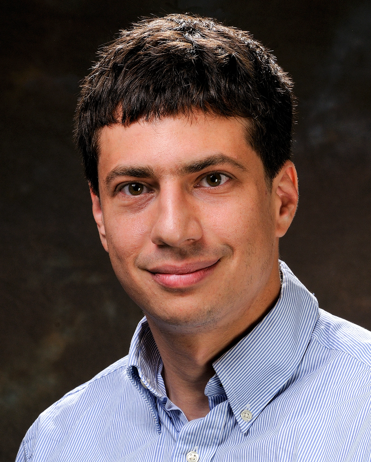 A smiling man in a blue button down shirt