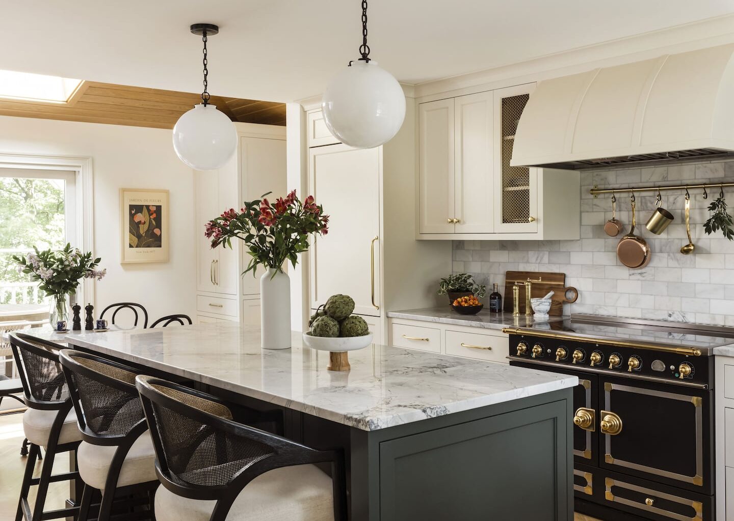 Kitchen with large center island with dark cabinets and white counter top. On the back wall there's a stove.