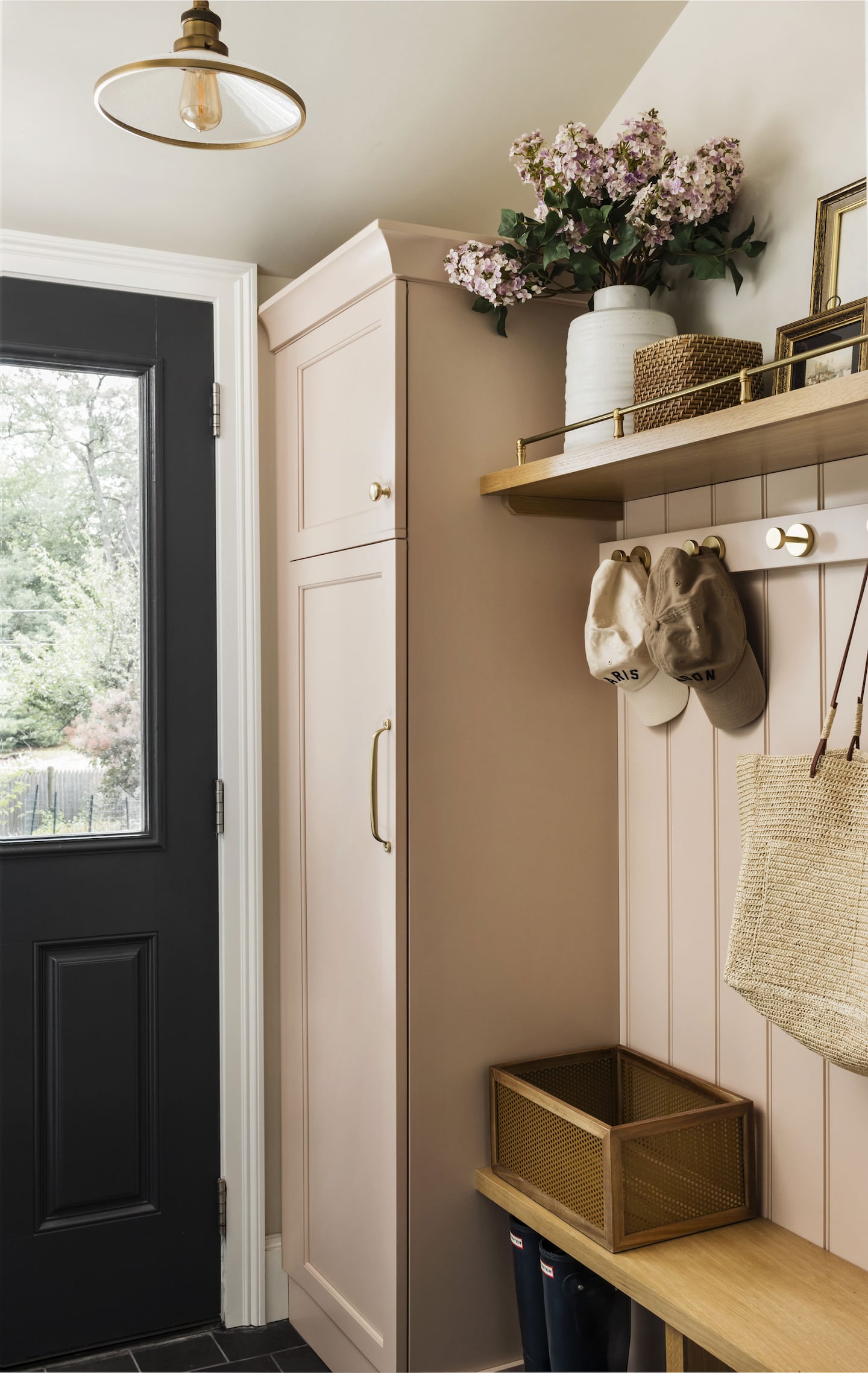 A hall entry way. The exterior door is on the left wall and on the right there's a built-in closet cabinet, bench, and coat hooks.