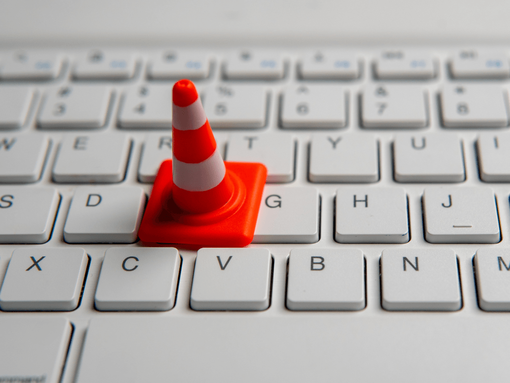 A small orange traffic cone placed on a white computer keyboard.