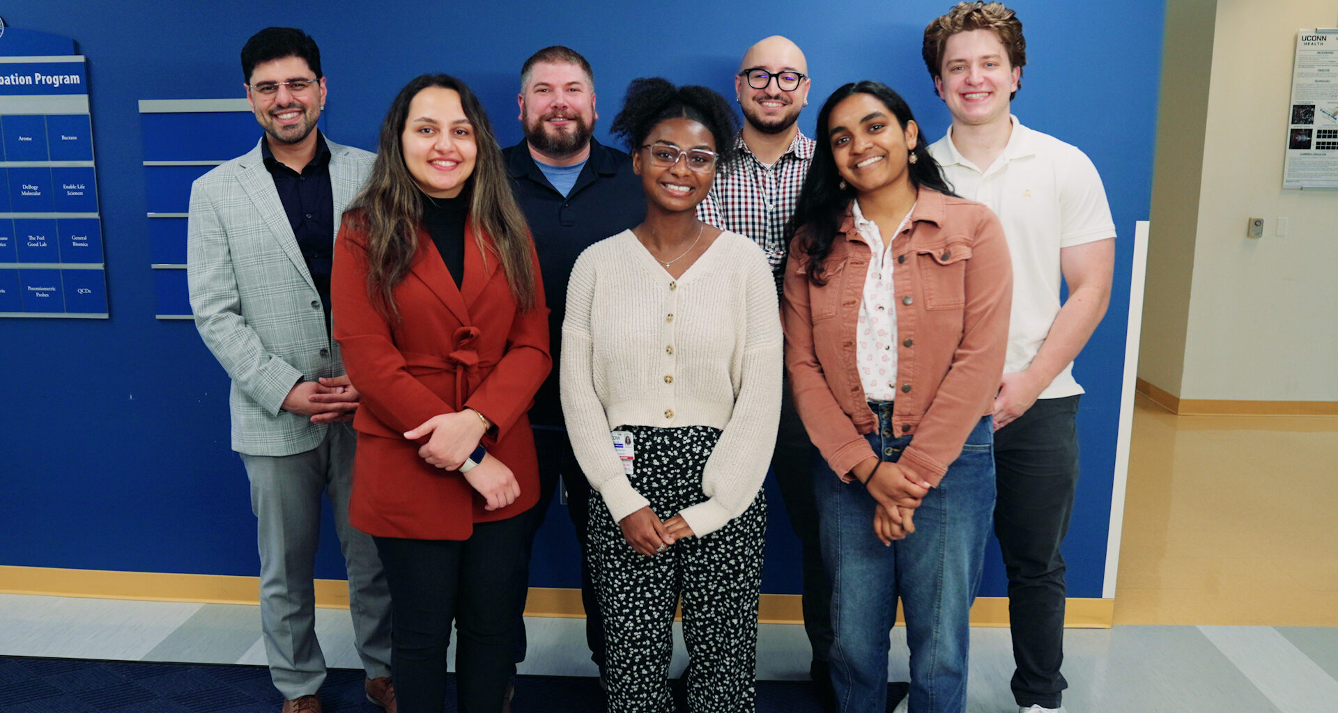 A group of researchers smiling in front of a blue wall
