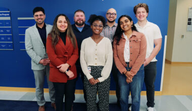 A group of researchers smiling in front of a blue wall