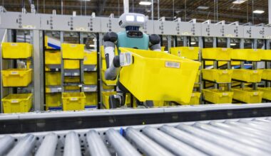 A humanoid robot lifting a yellow bin in a warehouse