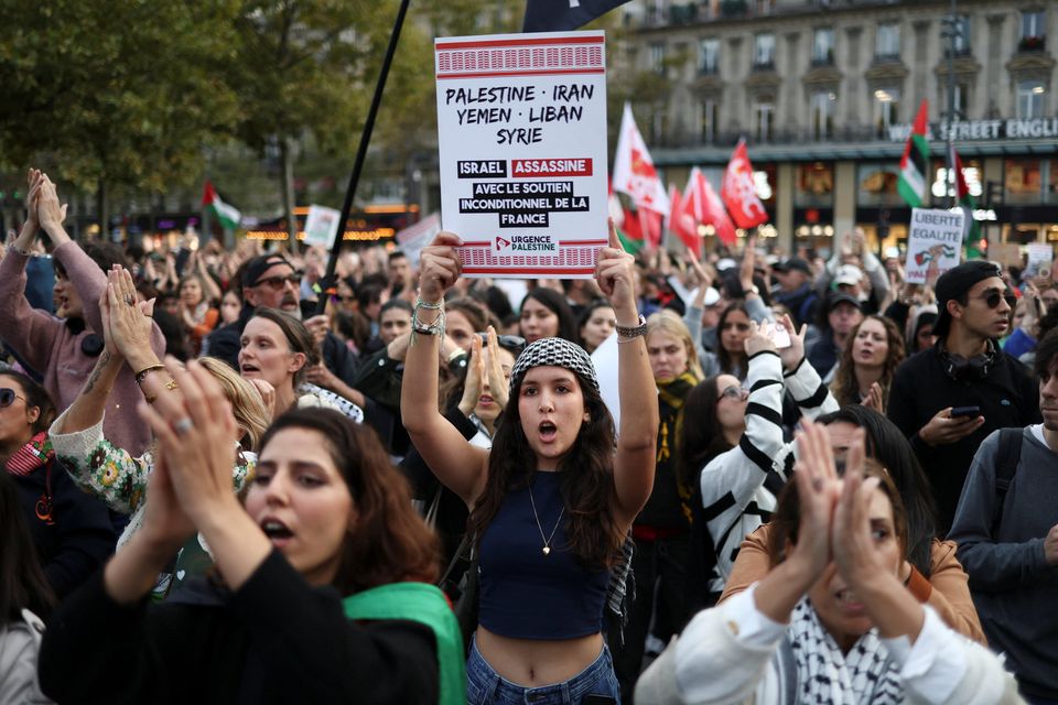 A demonstrator holds a placard that reads "Palestine, Iran, Yemen, Lebanon, Syria. Israel is assassinating with the unconditional support of France" during a protest to condemn the Israeli forces' interception of vessels of the Global Sumud Flotilla aiming to reach Gaza and break Israel's naval blockade, demanding the release of the flotilla's crews, and opposing Israel's operations in the Gaza Strip, amid the ongoing Israel-Hamas conflict, at the Place de la Republique in Paris, France, October 2, 2025. REUTERS/Tom Nicholson