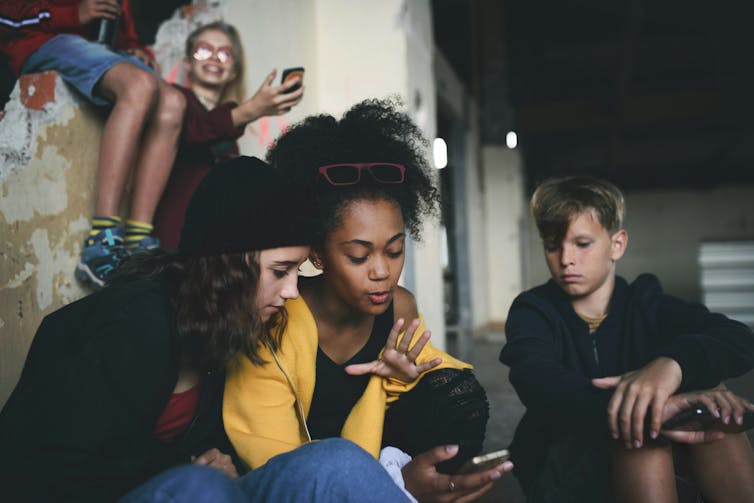 teenagers sitting looking at a mobile phone
