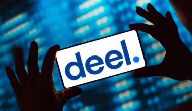 The Deel logo is shown on a smartphone screen held by silhouetted hands against a blue background.