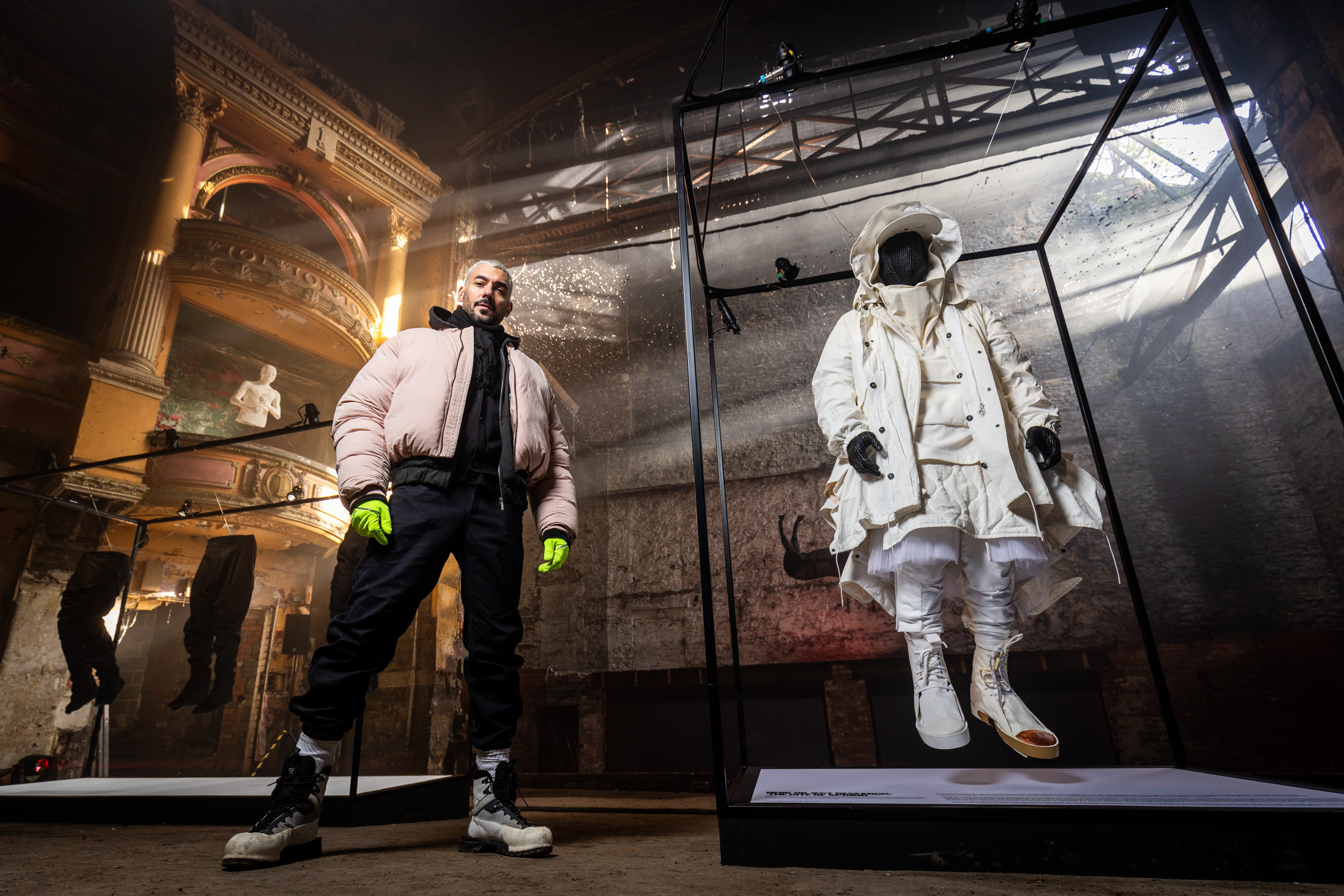 Designer Aitor Throup stands beside a display of garments from his retrospective exhibition inside the Empire Theatre in Burnley.