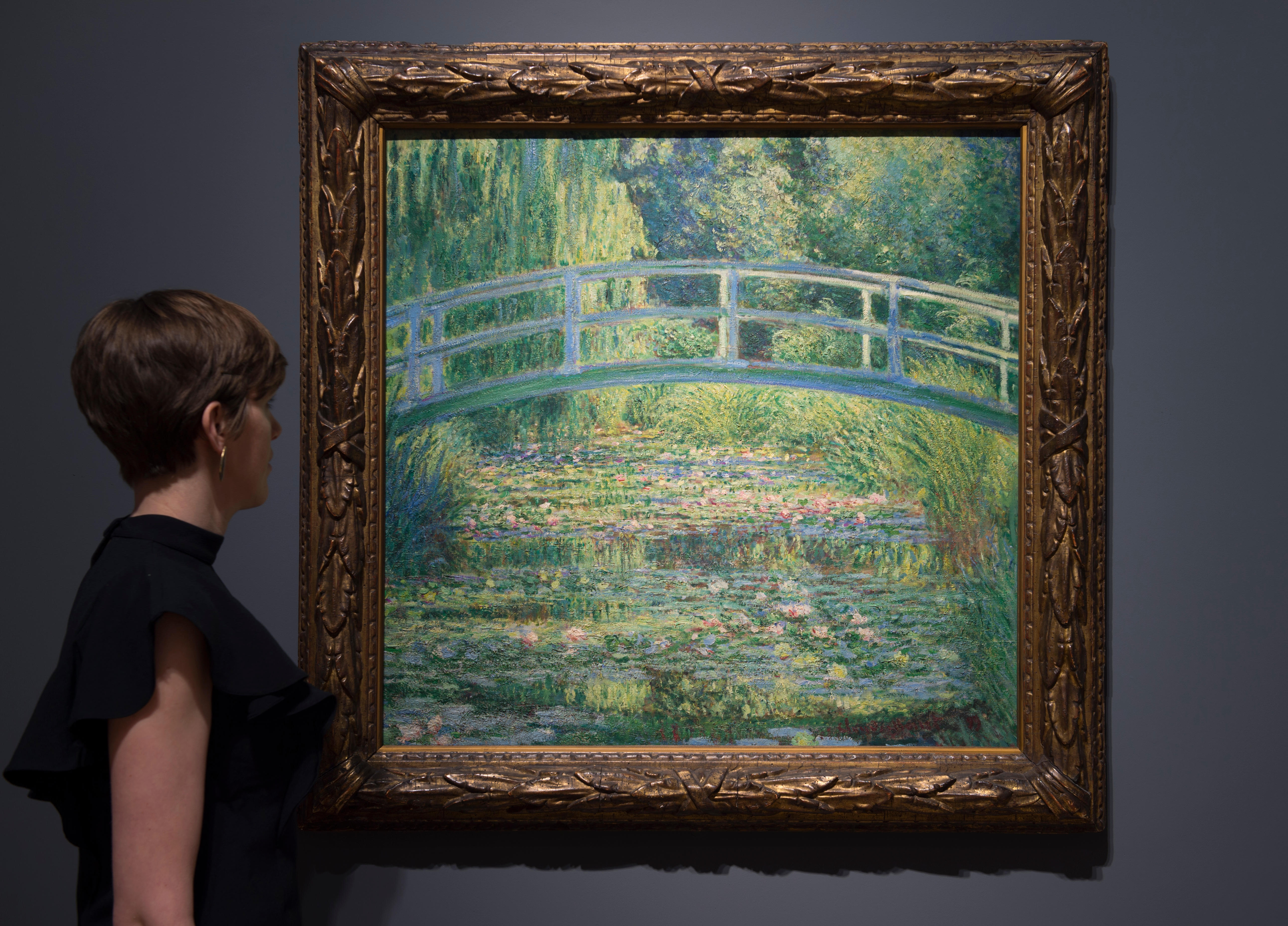 A person views Monet's "The Water-Lily Pond, 1899" painting.