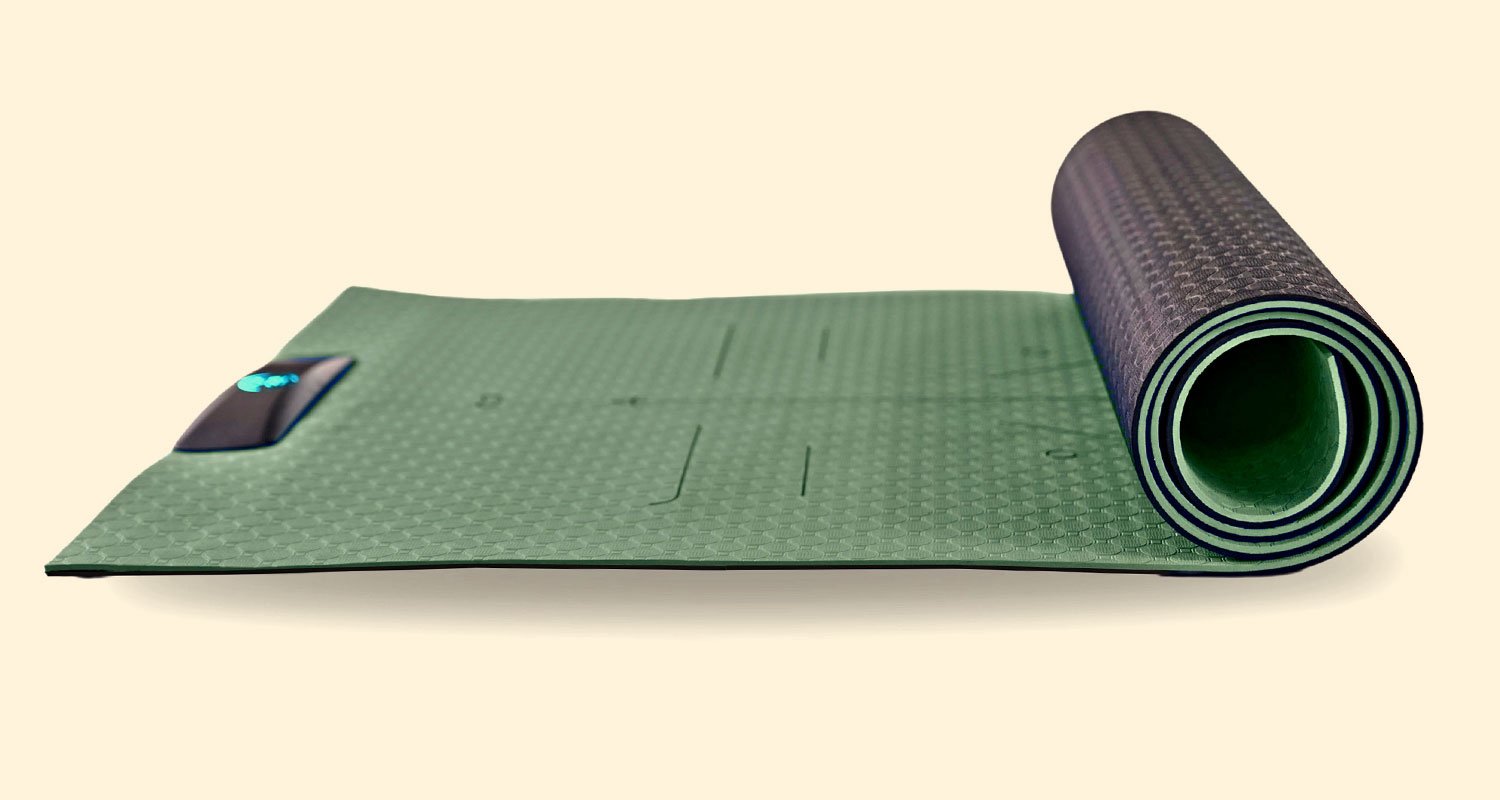 Rolled-up green yoga mat with alignment lines and a small electronic device.