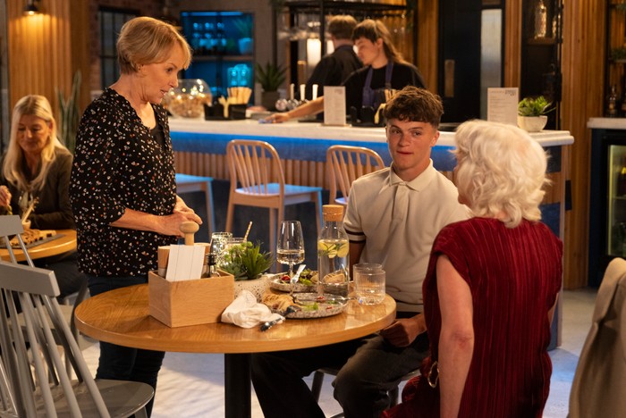 Sally stands over Trisha and her nephew in the Bistro in Coronation Street