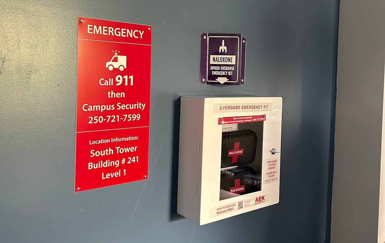 a sign telling people to call 911, then security and a box of naloxone