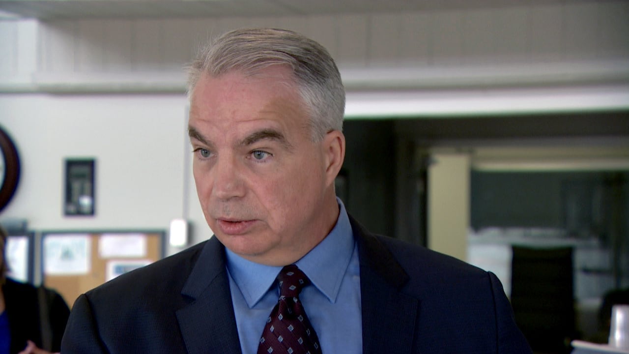 A man is a suit and tie holds his hands up at his sides.