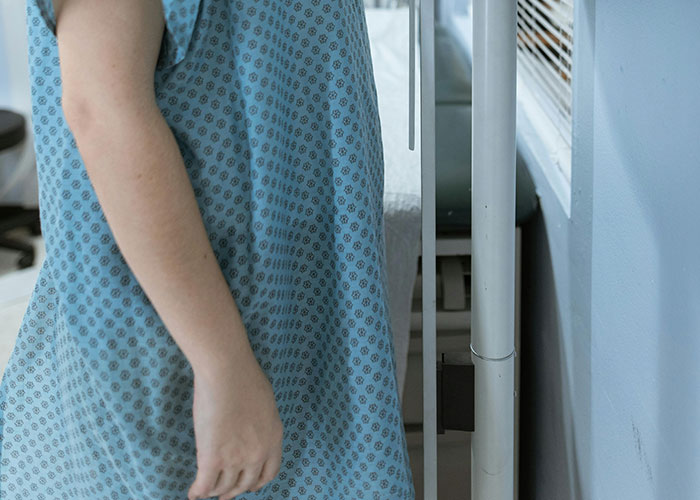 Patient wearing a blue gown inside a psychiatric institution, reflecting the experiences of psychiatric institution workers on the job.