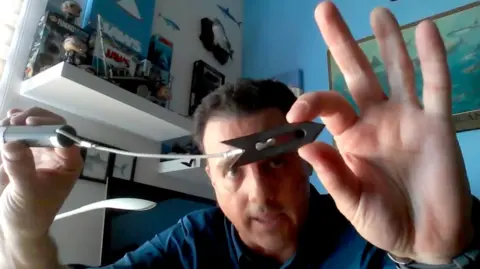 Mauricio Hoyos shows an acoustic tag, which is a cylinder, tied to a cable from which a metal point hangs