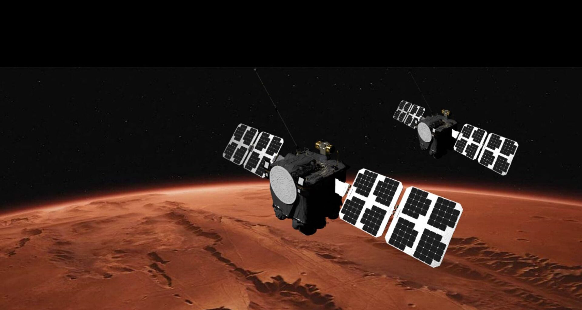 An illustration showing two large satellites with solar arrays on either side floating above the reddish-brownish surface of Mars.