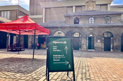 Ayshea Buksh/BBC sign  outside yard on cobbled stones