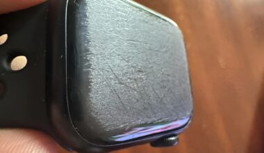 A close-up of a heavily scratched screen on an unbranded black smartwatch.