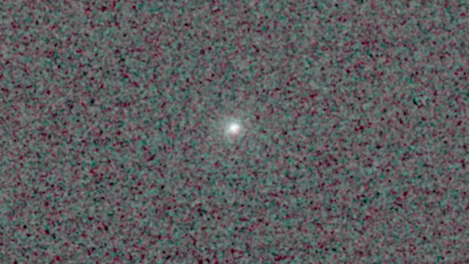 Comet 3I/ATLAS is feasible as a bright point of glowing light in the center of a pixelated black and dark grey background.