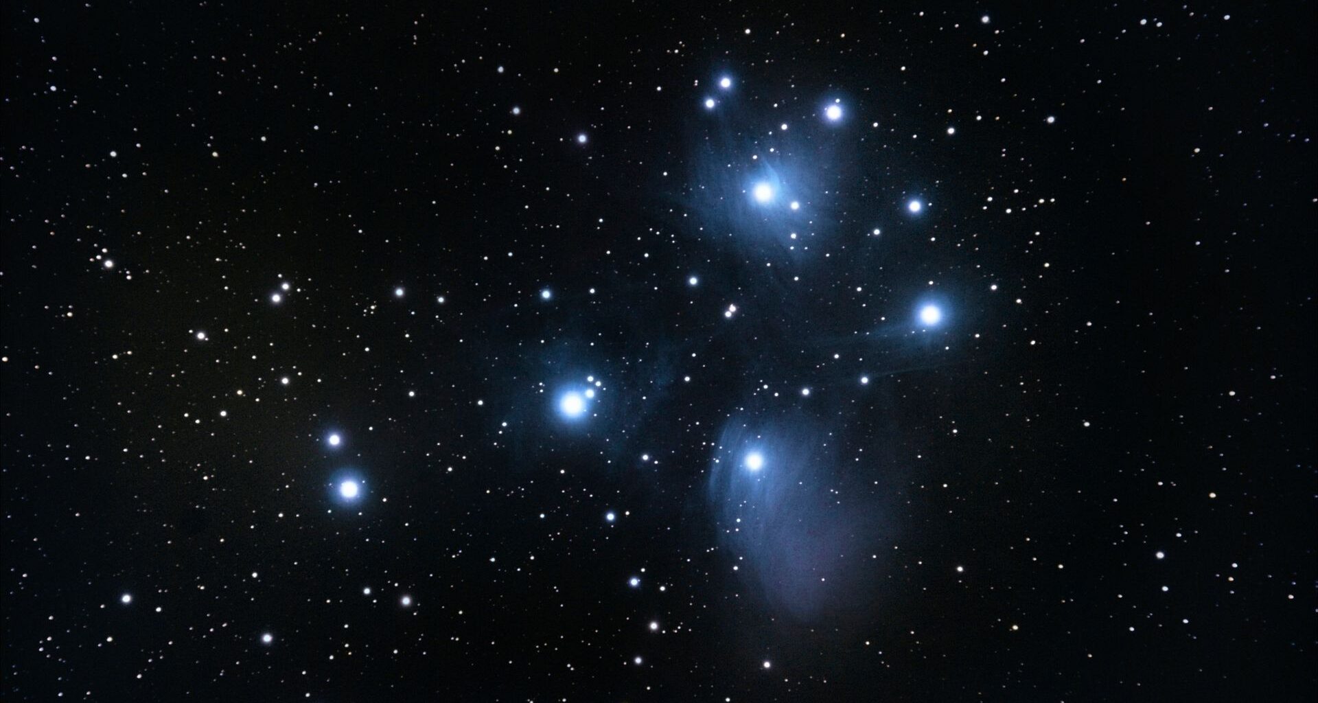 A series of bright blue and white stars shine in a deep space image
