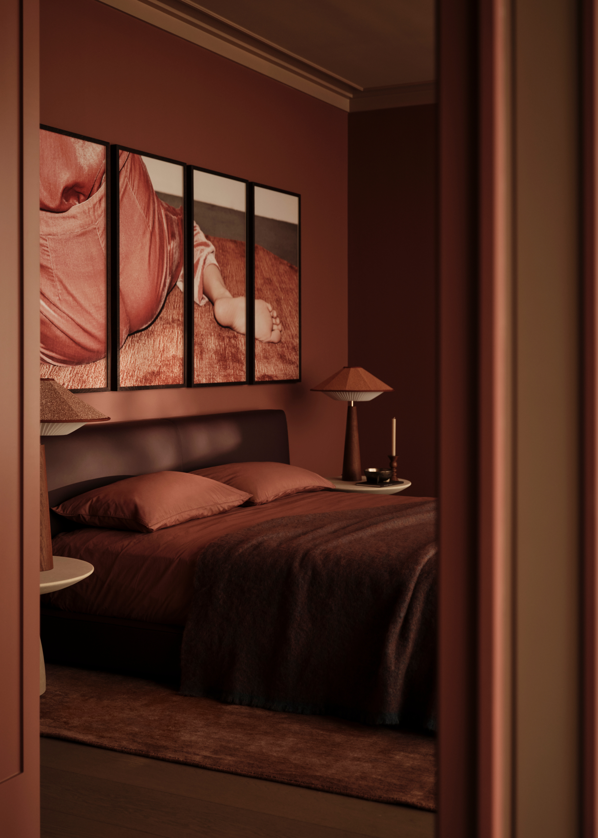 A modern bedroom decorated in warm, rich, cocooning tones with matching colored artwork of a child's foot and two matching modern bedside table lamps