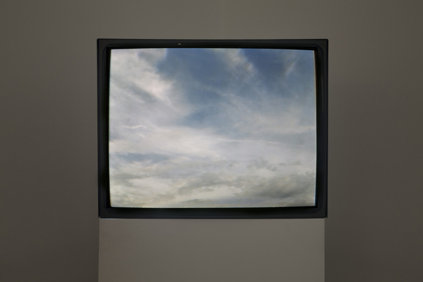 Vintage television displaying a serene sky with scattered white clouds on a plain background.