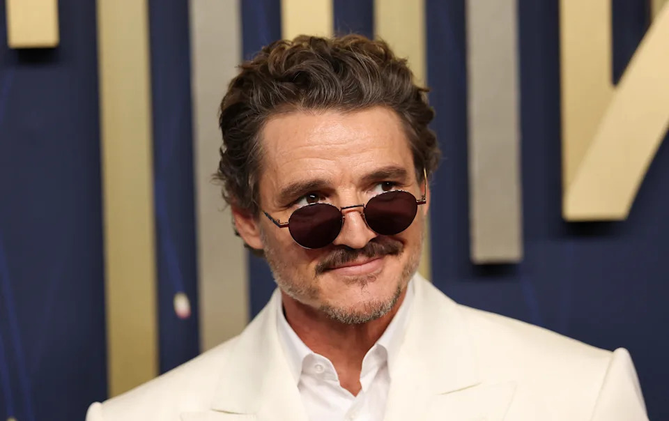 Person in a stylish white suit and round sunglasses at a formal event