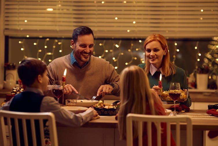 A family eats dinner at a candlelit table.