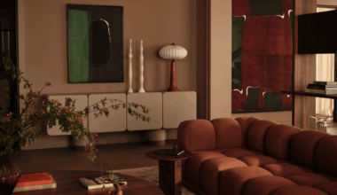 A modern living room with a contemporary rust sofa, earth tones, decorative accessories and artwork and a vase of foliage with berries on the round coffee table