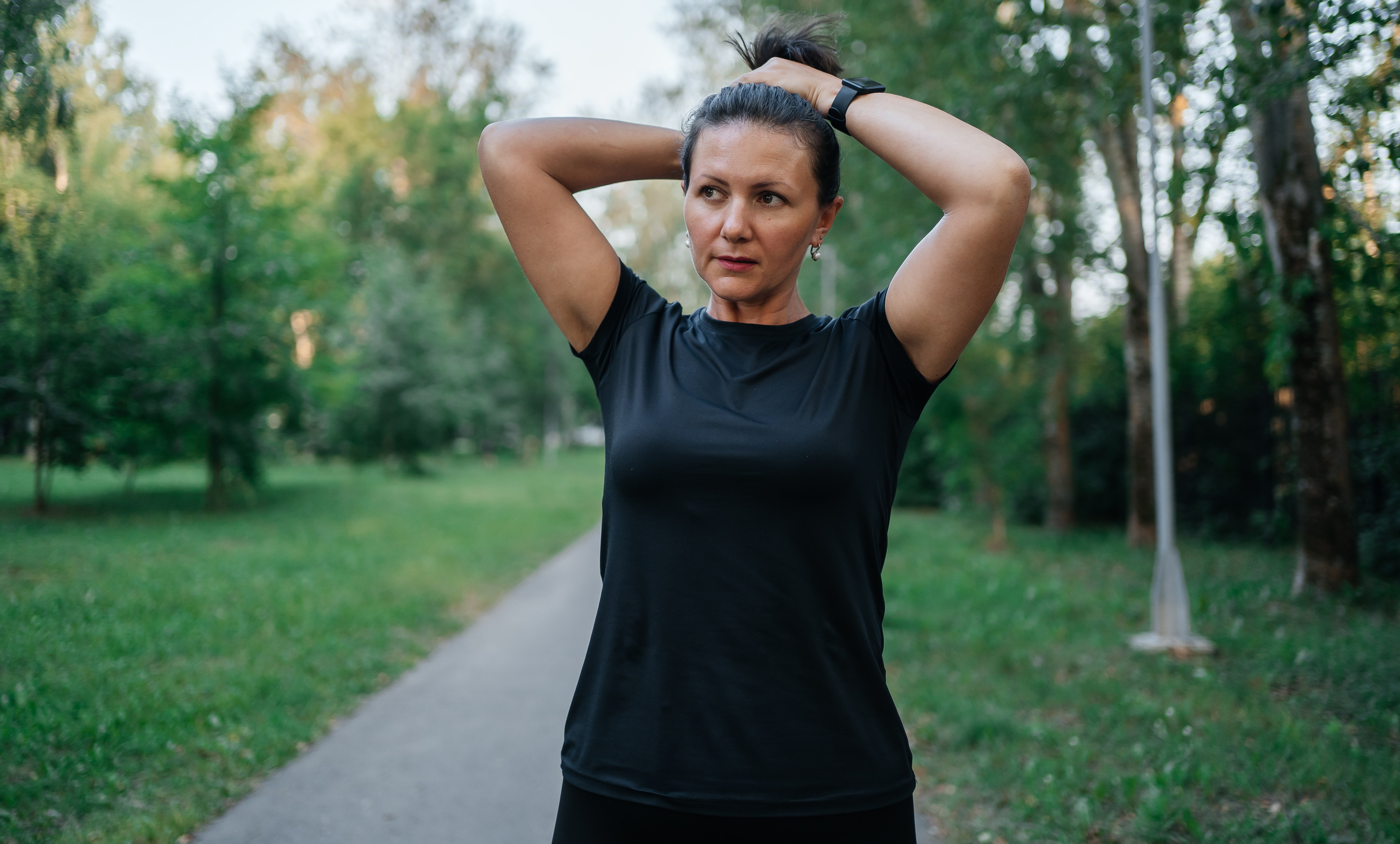 woman tying her hair in a ponytail before training outdoors