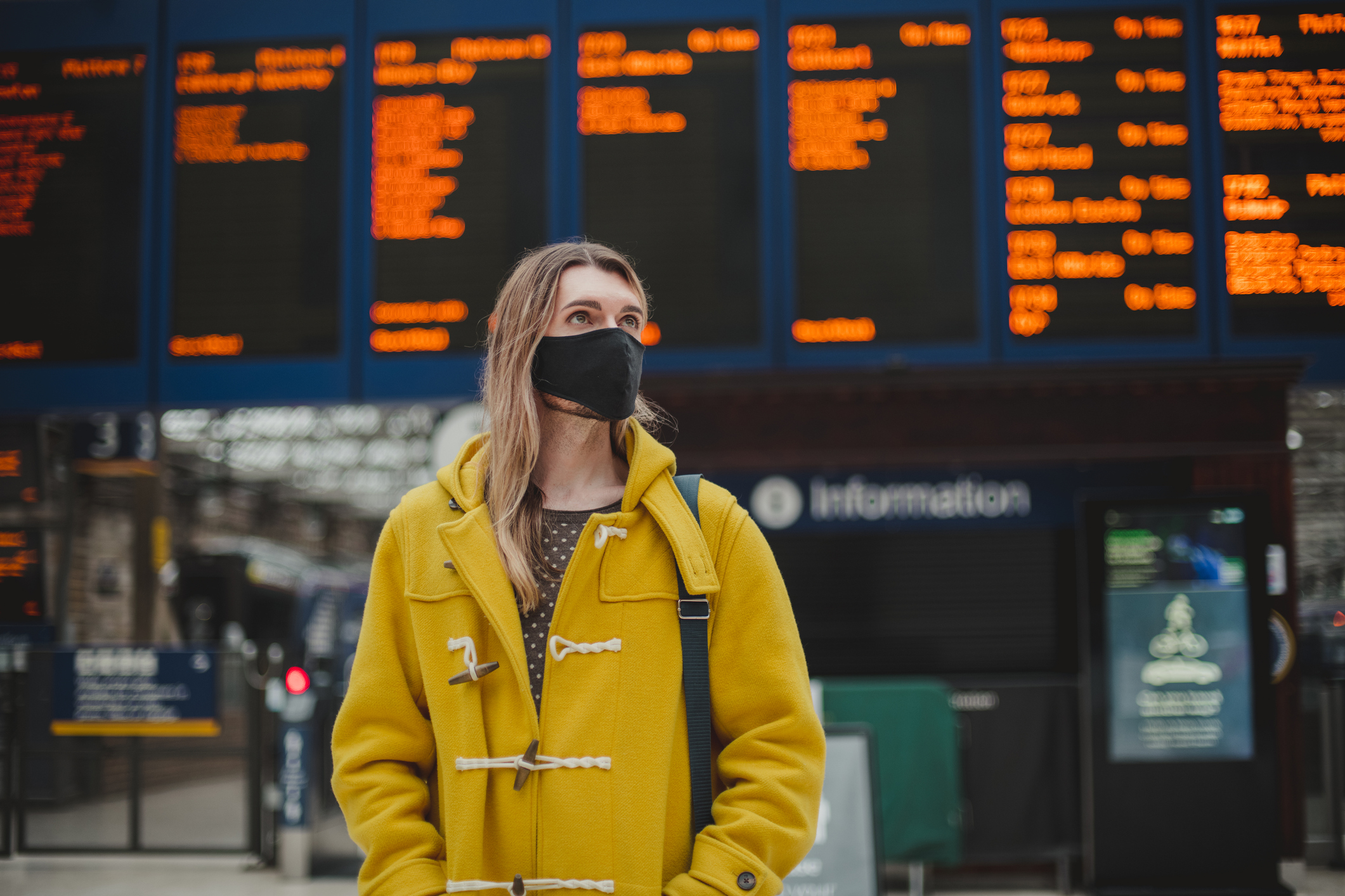 Young male commuter wearing a face mask at a train station.