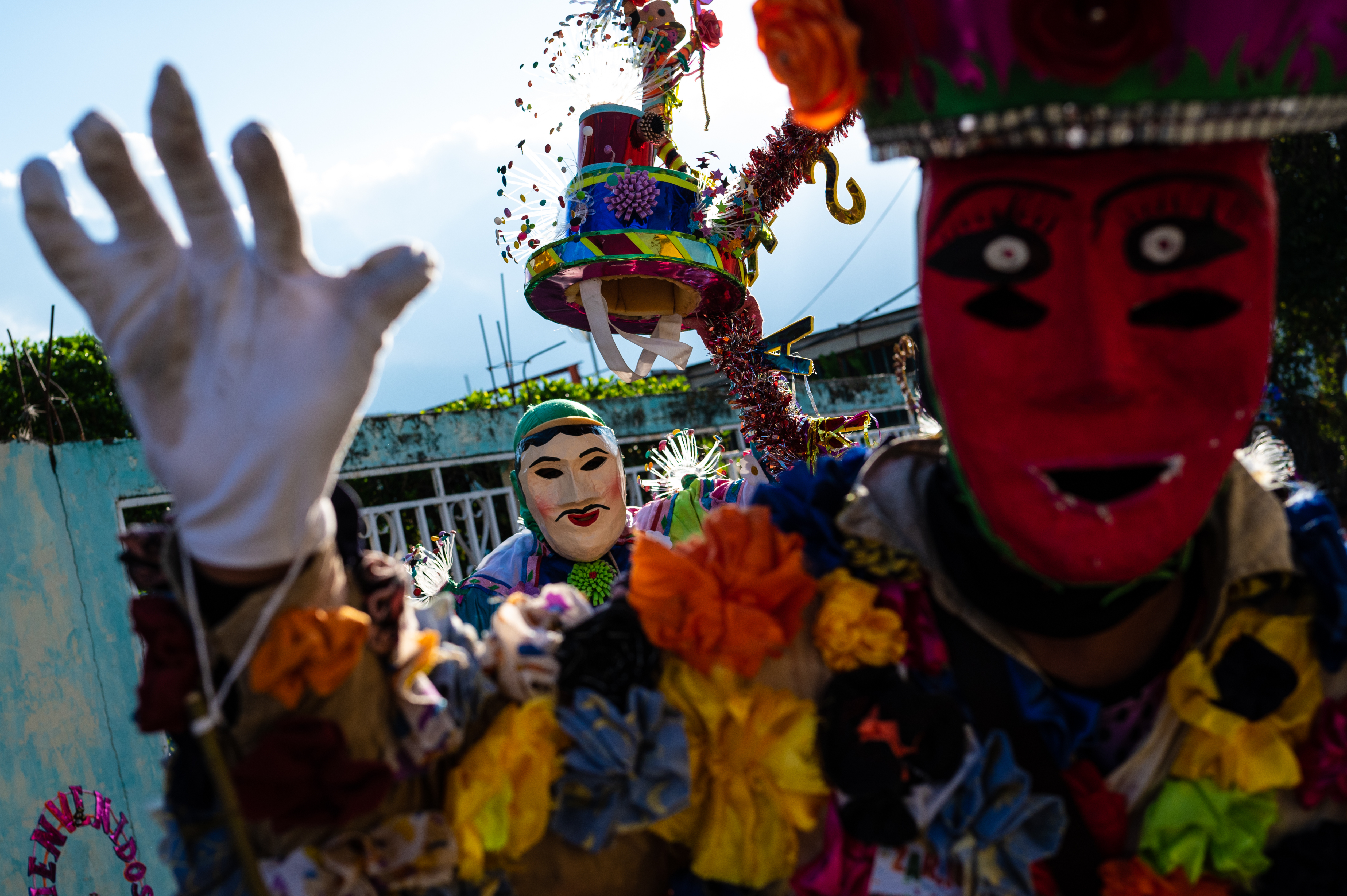 Close-up of a Zaragozas parade member with a red mask and a person wearing a white mask and green hat behind them.