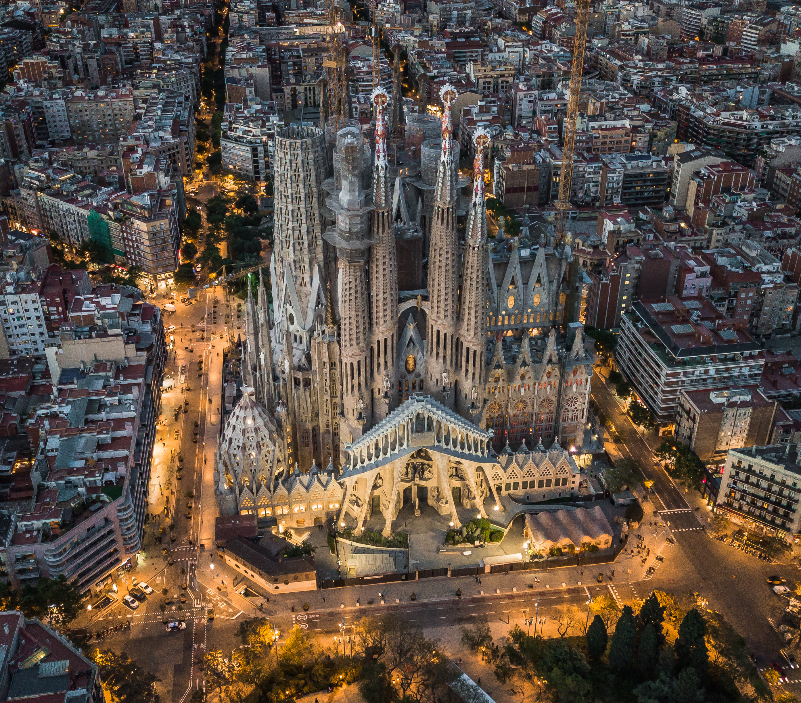 Aerial view of the Sagrada Familia basilica and surrounding illuminated city at night.