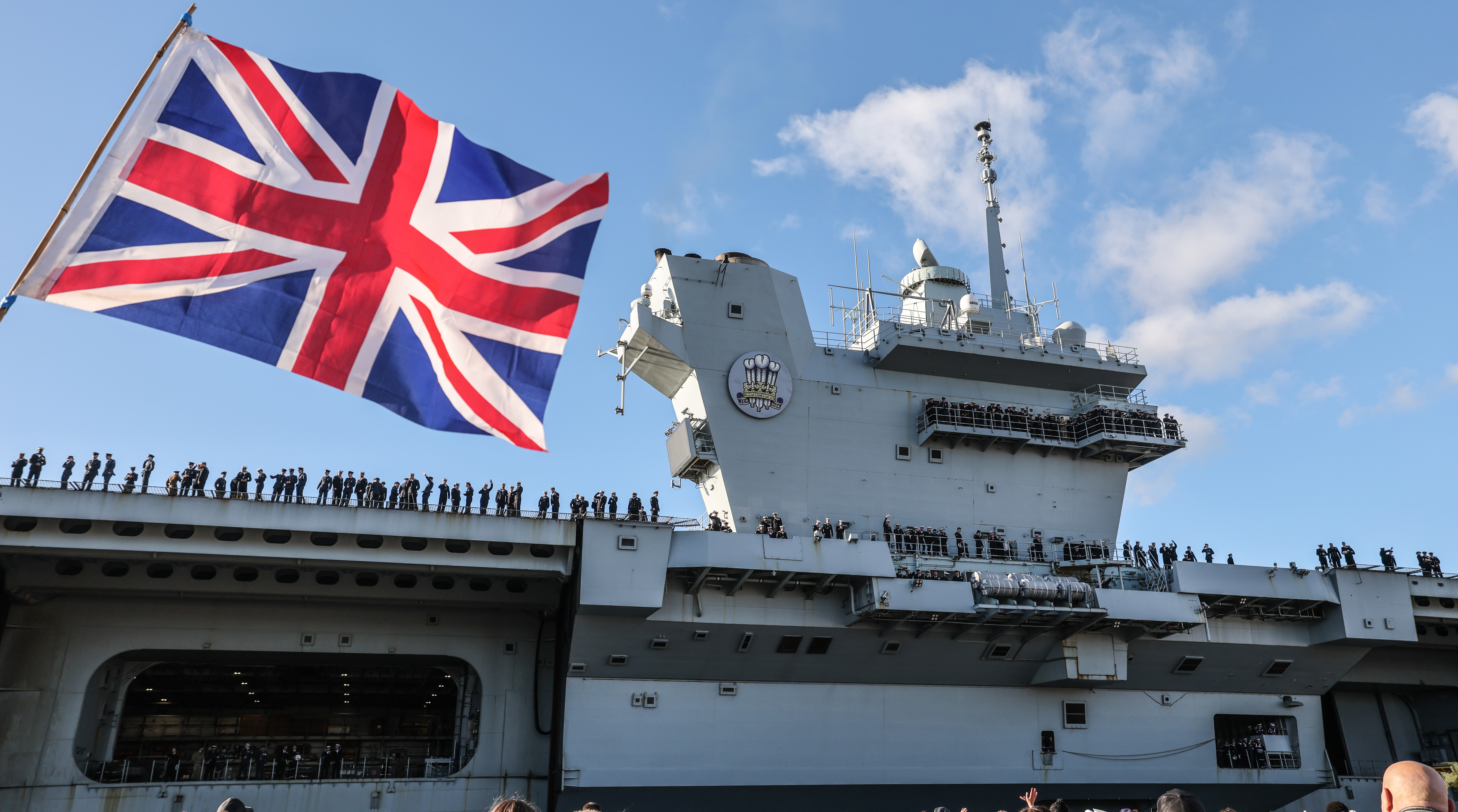 British aircraft carrier HMS Prince of Wales with a Union Jack flag in the foreground.
