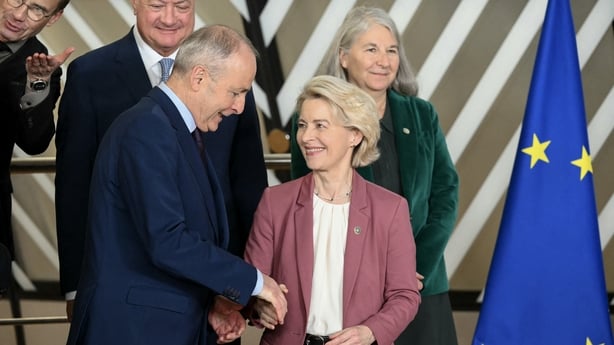 Two people shake hands on a stage 