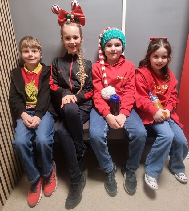 Four children sit together in Christmas clothes