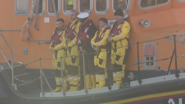 Members of the RNLI stand on the side of a boat
