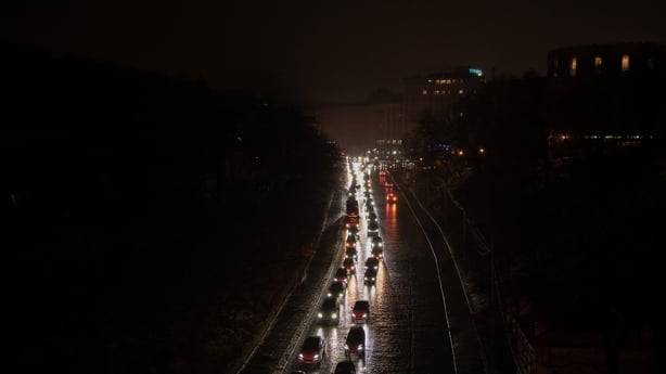 This photograph shows vehicles with headlights driving down a non-illuminated road during a power outage in Kyiv on December 27, 2025, following Russian missile and drone attacks on Ukrainian energy infrastructure amid the Russian invasion of Ukraine. Russia pummelled Ukraine's capital with drones a