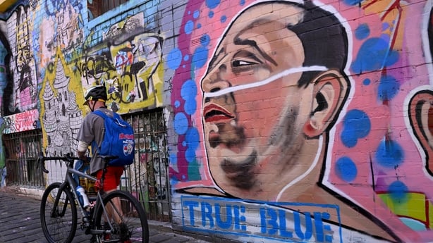 A man passes a mural by Jarrod Grech of Ahmed al Ahmed, the hero who was filmed tackling and disarming one of the attackers in the Bondi Beach mass shooting
