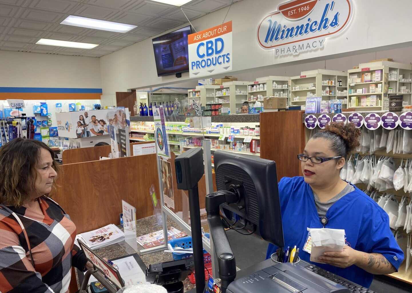 Customer Lisa Durs is helped by pharmacy clerk Kira Tomoney at Minnich