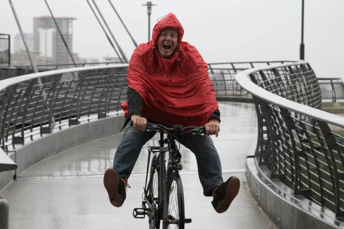 Stock image of a man on a bike in the rain 