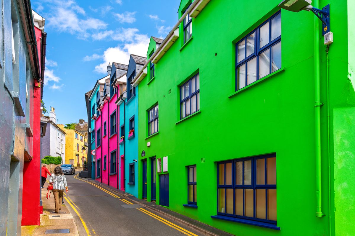Pedestrians walk the narrow streets and alleys of brightly colored homes and shops in Kinsale Village, a historic port and fishing town in County Cork, Ireland.