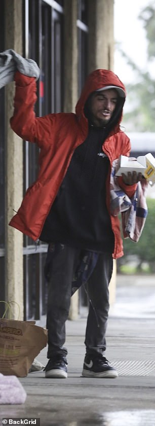 The one-time child star kept warm in a red coat over a black hooded sweatshirt with gray pants and black Nike sneakers on the winter day