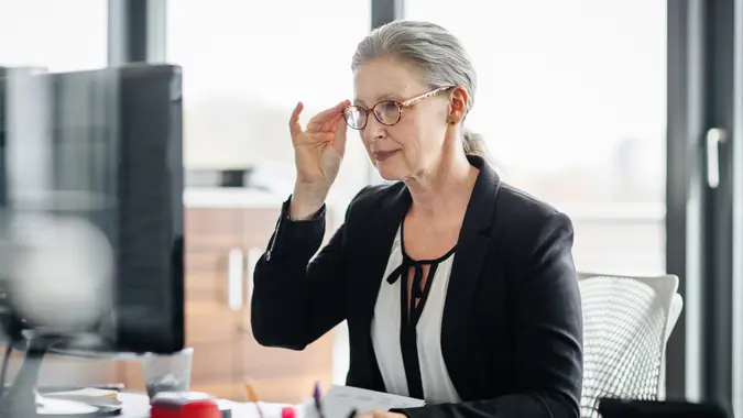 Portrait of a senior businesswoman sitting on her desk in a modern office and.