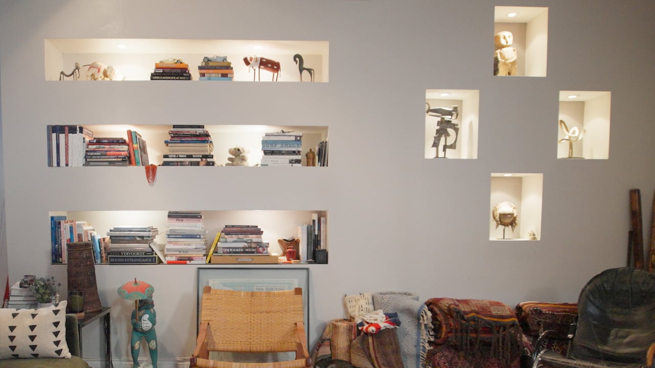 Closeup on built-in bookshelves in a living room. The shelves contain art and books. 