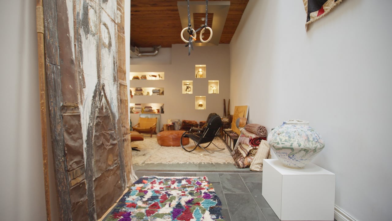 Exercise rings hang from the ceiling in a hallway leading to a living room.