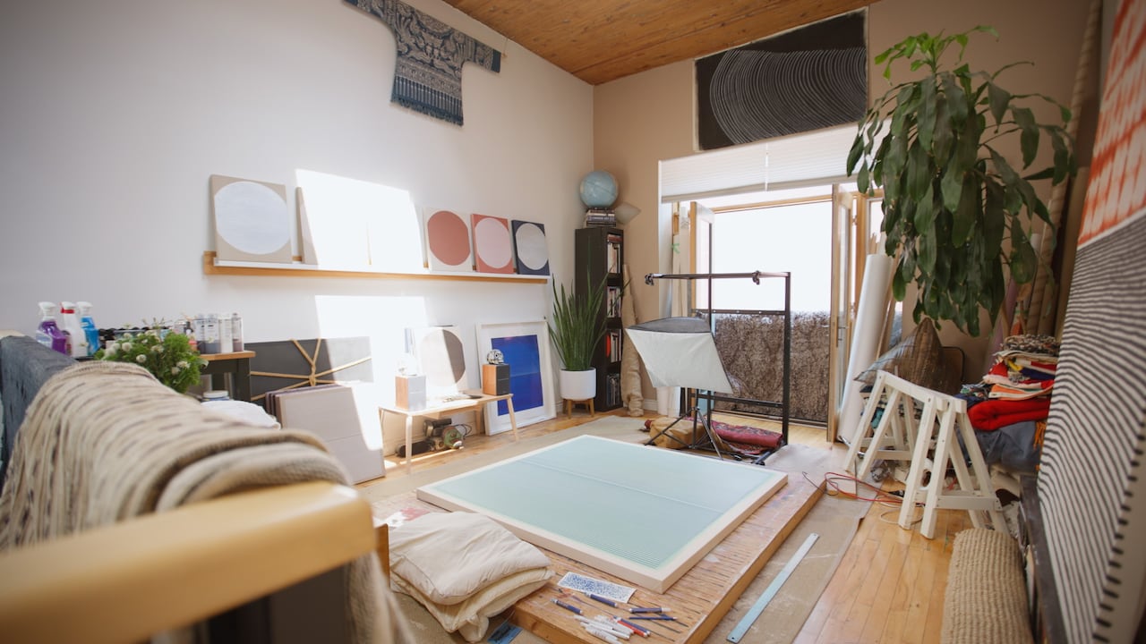 A studio space in the home with artwork on the walls and lots of light from the window. 