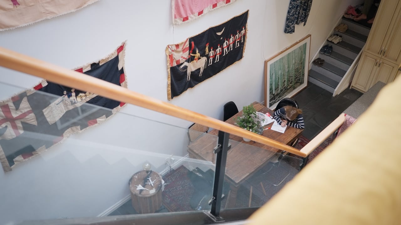 A stairway with a glass railing and flags on the wall behind it. 