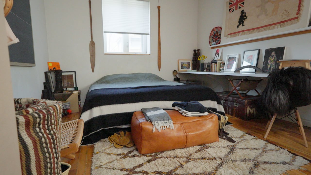 A bedroom with a low bed and lots of artwork on the walls. 