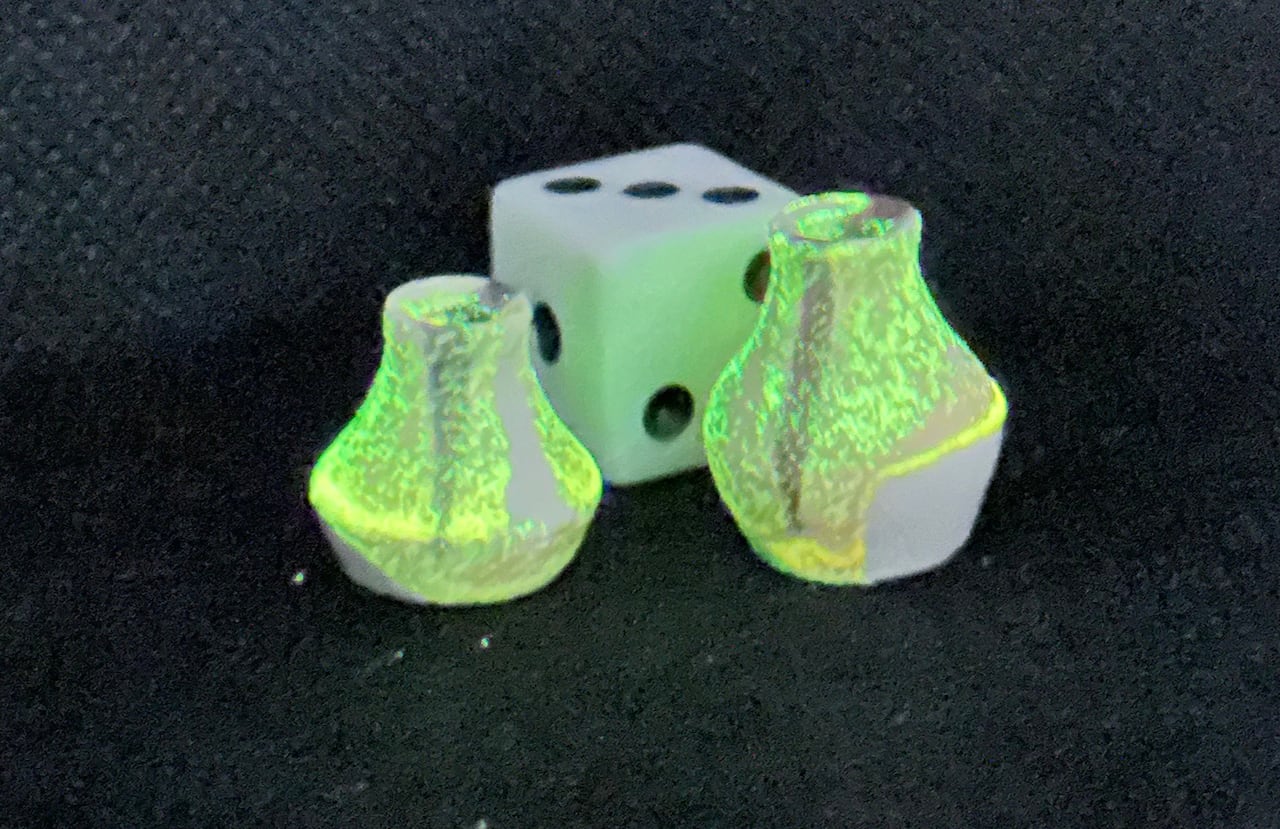 Two tiny neon green vases sit next to a die, placed there for scale. 
