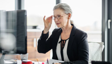 Portrait of a senior businesswoman sitting on her desk in a modern office and.
